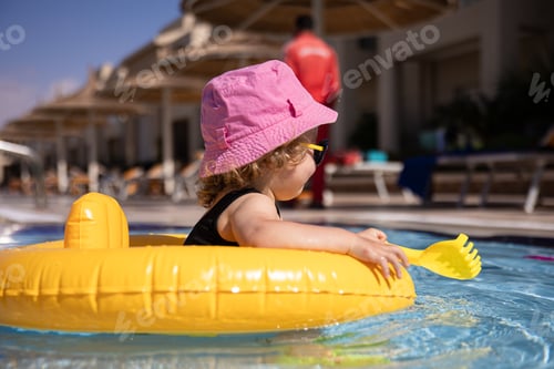 Preview: A funny little girl plays in the pool while sitting in a swimming circle.