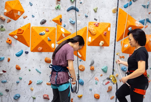 Preview: Smiling Asian women in sportswear posing near the bouldering training w