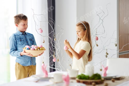 Preview: Girl and brother decorating twigs with colourful easter eggs