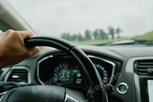 Preview: Driver hands on steering wheel. Driving car in rainy day