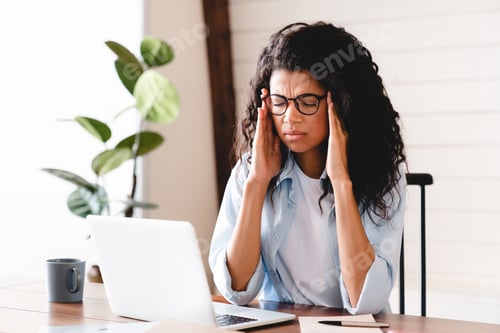 Preview: Exhausted young african-american businesswoman having headache in office.