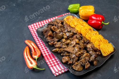 Preview: bottom view chicken liver fry with potato on platter colored bell peppers on table