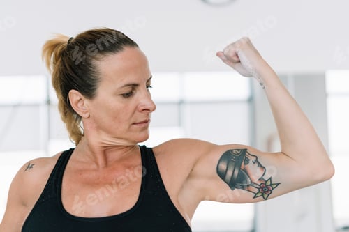 Preview: Sportswoman flexing tattooed arm