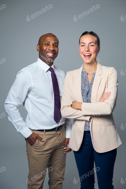 Preview: Studio Portrait Of Smiling Businessman And Businesswoman Wearing Suits Against White Background