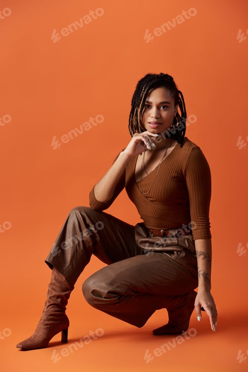 Preview: Stylish young woman with braided hair poses gracefully in a vibrant studio setting