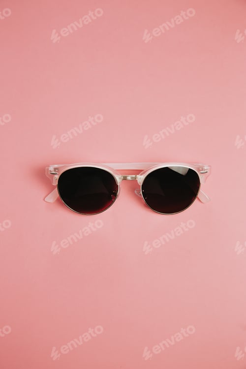 Preview: Minimalistic shot of a pair of sunglasses over a pastel pink background with copy space