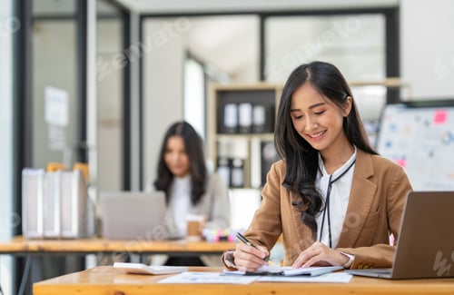 Preview: Asian businesswomen work using laptops and tablets, calculators to calculate make an account analysi