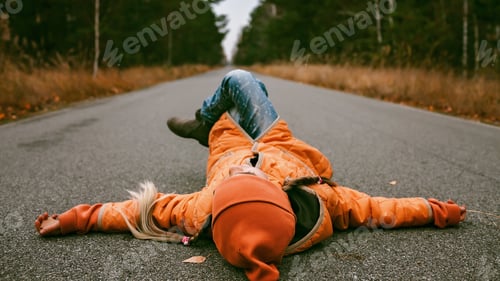 Preview: Girl lays on the road in fall forest. Emotional feeling, thinking, mental health. Autumn vibes