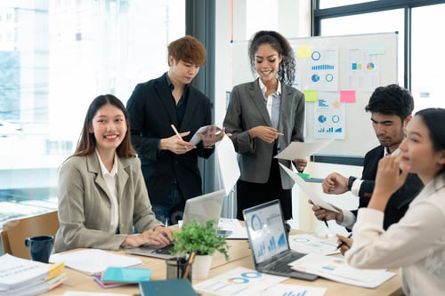 Preview: Group of young businessman talking with young and mature colleagues in boardroom at meeting