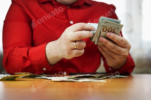 Preview: closeup of male hands counting a stack of US one hundred dollar bills