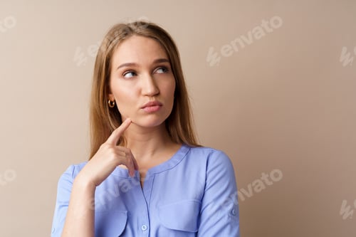 Preview: Pensive young businesswoman thinking about some idea against beige background