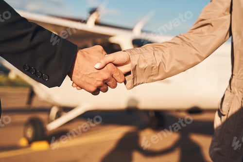 Preview: Business colleagues shaking hands outdoors at airdrome