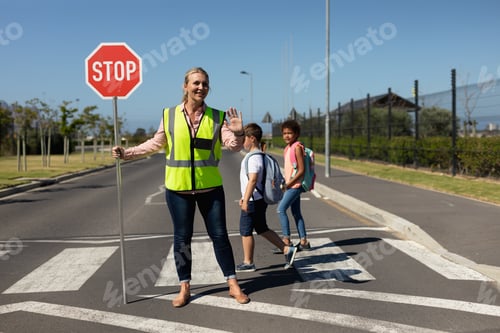 Preview: Woman wearing a high visibility vest and holding a stop sign