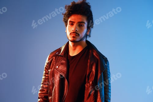 Preview: Portrait of a stylish man with curly hair on a blue background multinational, colored light, black