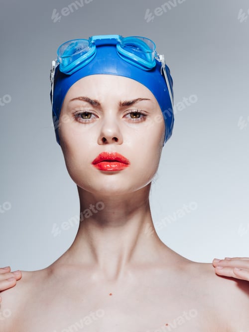 Preview: Woman in blue goggles swimming cap naked shoulders light background