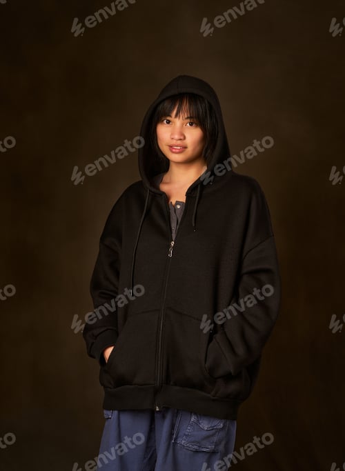 Preview: A woman in a black hoodie is standing in front of a dark background