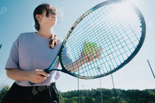 Preview: Close up image tennis player woman serving to start a new game, racket in front with tennis ball.