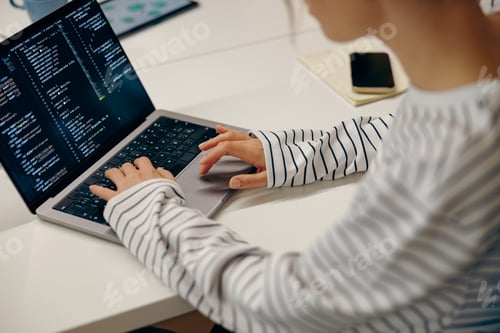 Preview: Close up of young female computer programmer is coding at laptops while sitting in coworking