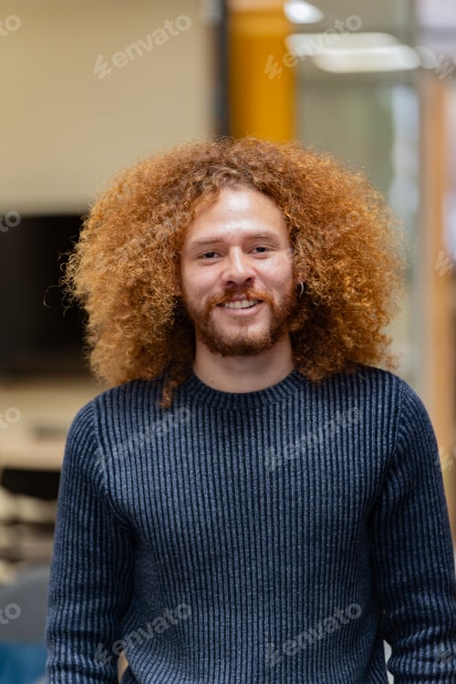 Preview: Happy man with curly hair in a knitted sweater.