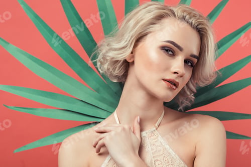 Preview: portrait of sensual blonde woman in lace bra, isolated on red with palm leaf