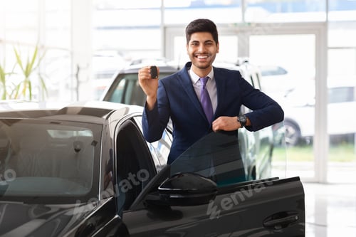 Preview: Middle-eastern businessman showing car key and smiling