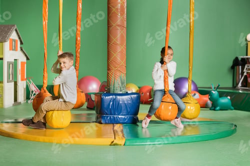 Preview: adorable smiling siblings swinging and playing in entertainment center