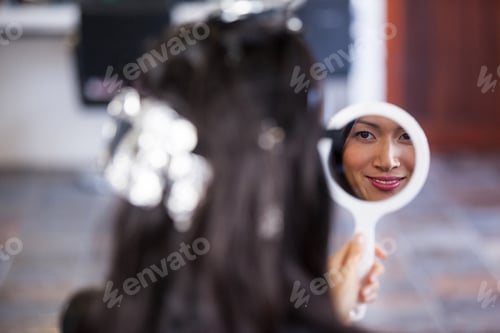 Preview: Woman looking at mirror while waiting with hair dye in her head