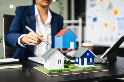 Preview: A businesswoman is reviewing contract papers at her desk in a sustainable house and condo