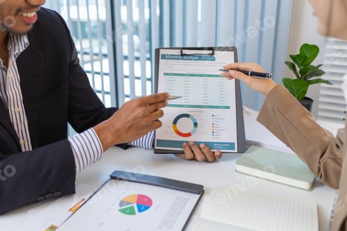 Preview: Business colleagues are engaged in a financial meeting, reviewing colorful charts and reports.