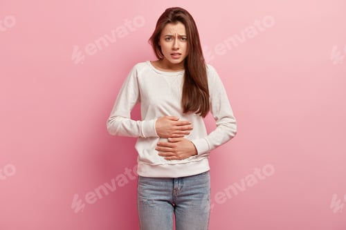Preview: Upset European woman keeps hands on belly, suffers from pain, feels discomfort after eating fast foo
