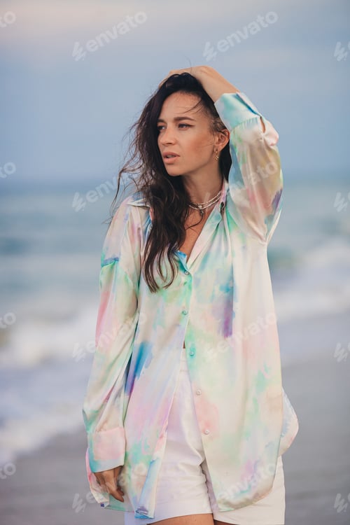 Preview: Young happy woman on the beach enjoy her summer vacation. Woman walking along the sea in evening.