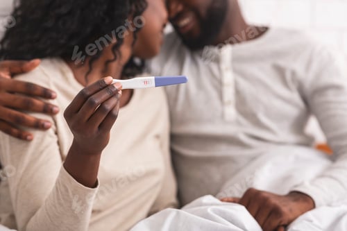 Preview: Happy african american couple showing pregnancy test with positive result