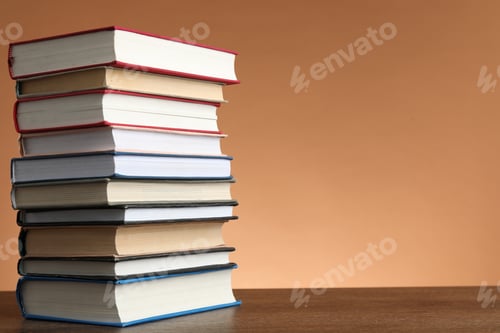 Preview: Stack of many books on wooden table against light brown background, space for text