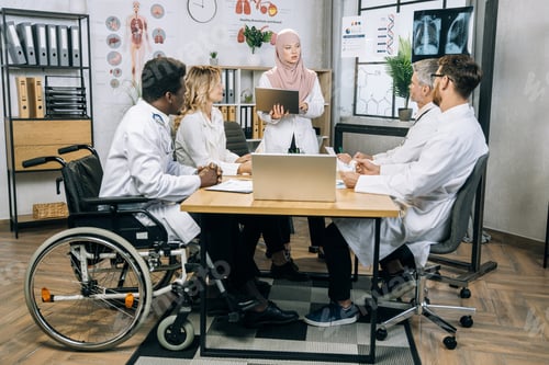 Preview: Doctor in hijab having conference with diverse colleagues