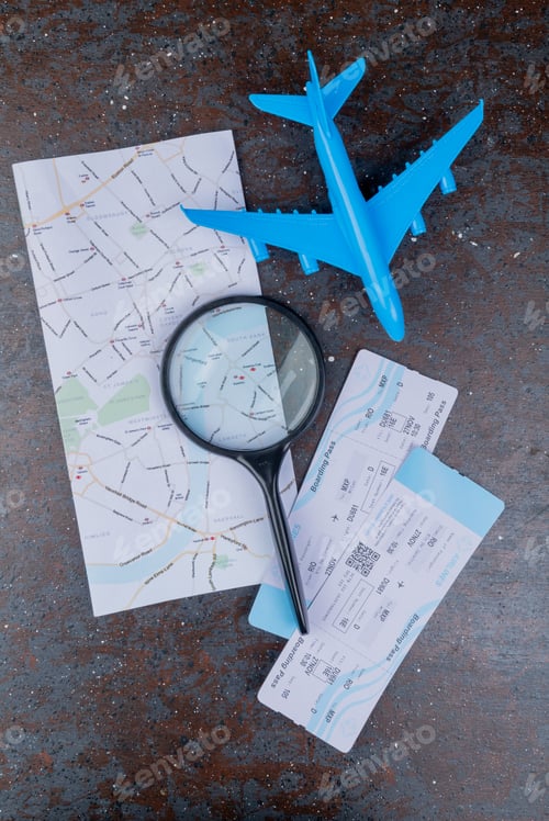 Preview: top view of black magnifying glass on a map and plane tickets with blue model plane