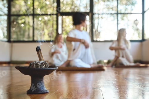 Preview: Sandalwood stick with meditating people group doing yoga on background.