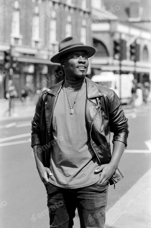 Preview: Happy male wearing hat is smiling and standing in a London street.