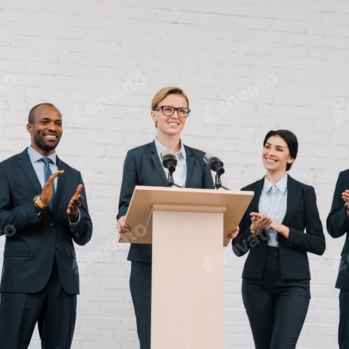 Preview: happy multicultural businessmen and businesswoman applauding to attractive speaker