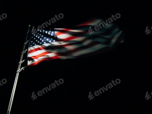 Preview: American flag emerging from the darkness with light shining on United States stars and stripes