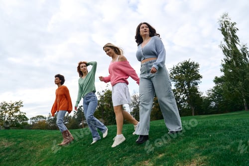 Preview: Fashion forward friends walking confidently in a vibrant spring park