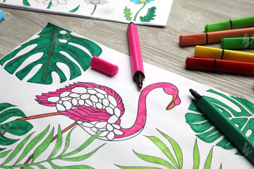 Preview: Coloring page with children drawing and set of felt tip pens on wooden table, closeup