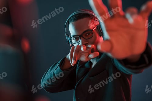 Preview: Futuristic neon lighting. Young african american man in the studio