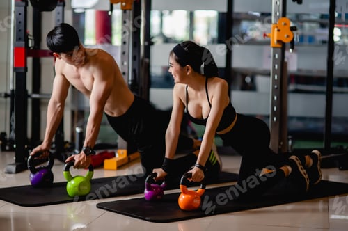Preview: Young couple doing plank on kettlebell workout at fitness gym