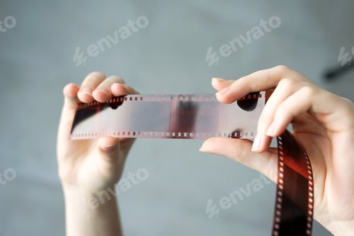 Preview: Analog photography on filmstrip . Hands holding photo negatives against the light. Retro style