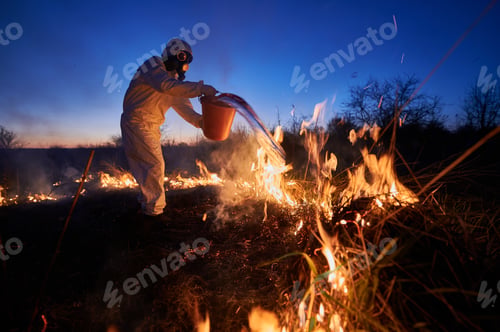 Preview: Fireman ecologist extinguishing fire in field in the evening