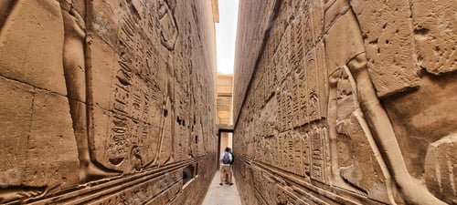Preview: People strolling along an ornately embellished brick alleyway leading to an ancient building