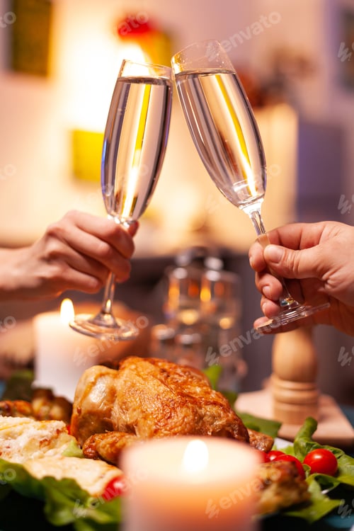 Preview: Closeup of couple hands hitting glass of wine during christmas dinner