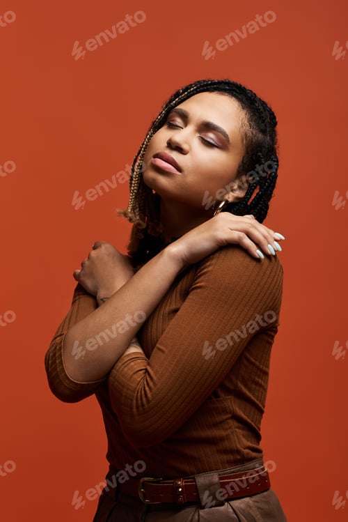 Preview: Stylish young African American woman posing gracefully in a vibrant studio with braided hair