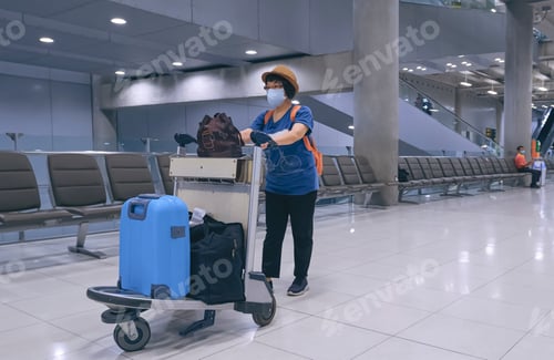 Preview: Asian female tourist wearing face masks with luggage walking in airport terminal