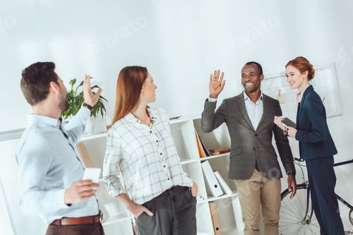 Preview: smiling multicultural businesspeople waving hands in office